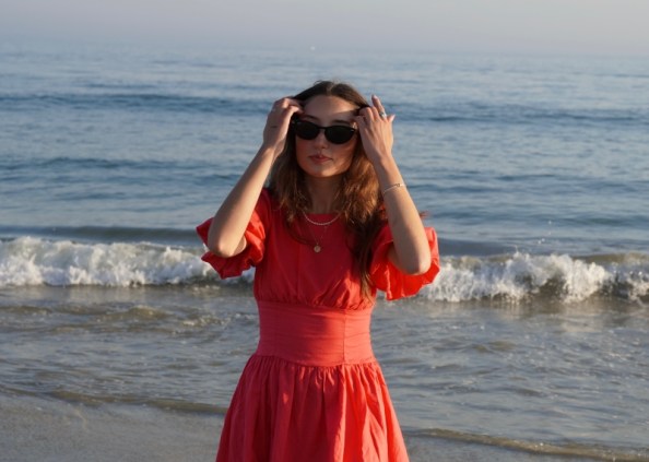 Erin Gibney standing on the beach with a small wave crashing behind her